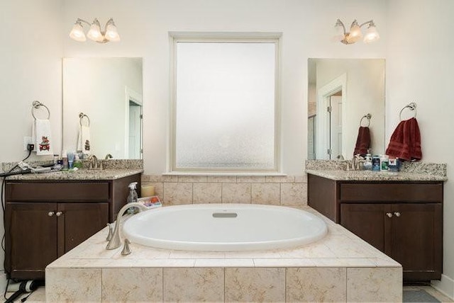 bathroom with tiled tub and vanity