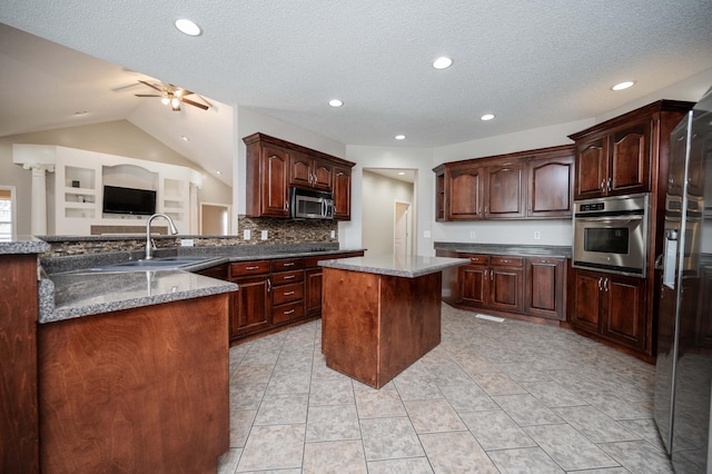 kitchen with appliances with stainless steel finishes, ceiling fan, sink, a kitchen island, and lofted ceiling