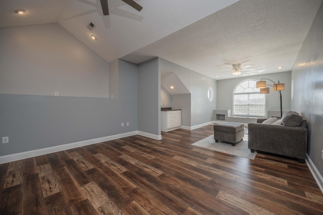 living room with a textured ceiling, ceiling fan, dark wood-type flooring, and vaulted ceiling