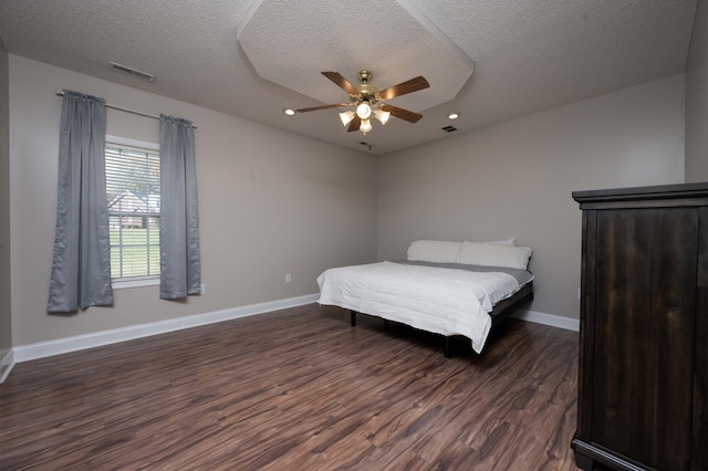 bedroom featuring ceiling fan, dark hardwood / wood-style floors, and a textured ceiling