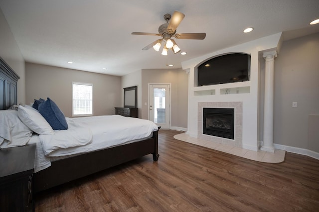 bedroom featuring ceiling fan, a fireplace, and dark wood-type flooring