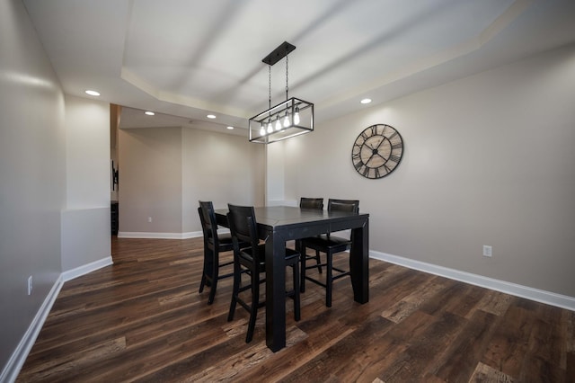 dining area featuring a raised ceiling and dark hardwood / wood-style floors