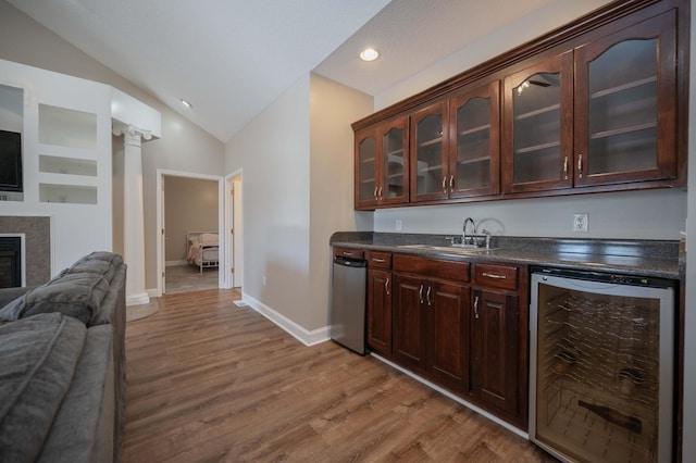 bar featuring dark brown cabinetry, a tile fireplace, sink, wine cooler, and vaulted ceiling