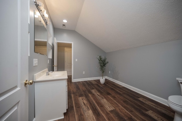 bathroom featuring hardwood / wood-style floors, vanity, lofted ceiling, toilet, and a textured ceiling