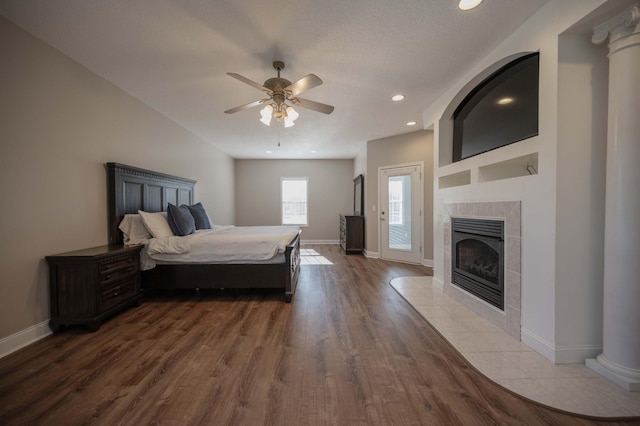 bedroom featuring a tile fireplace, ceiling fan, and hardwood / wood-style flooring