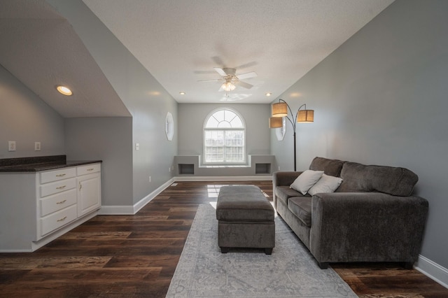 living room with dark hardwood / wood-style floors, ceiling fan, lofted ceiling, and a textured ceiling