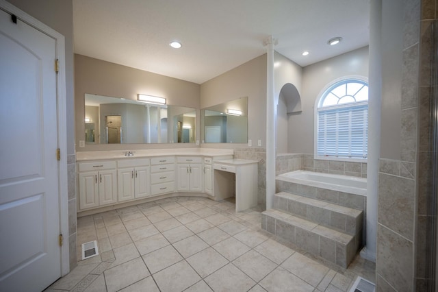 bathroom featuring vanity, tile patterned floors, and tiled tub