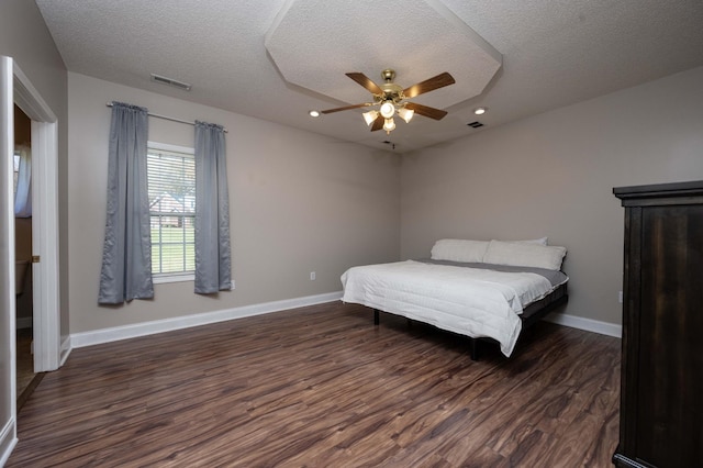 bedroom with ceiling fan, dark hardwood / wood-style flooring, and a textured ceiling