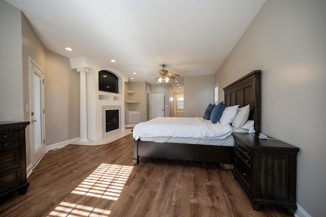 bedroom featuring a tiled fireplace, ceiling fan, and dark hardwood / wood-style floors