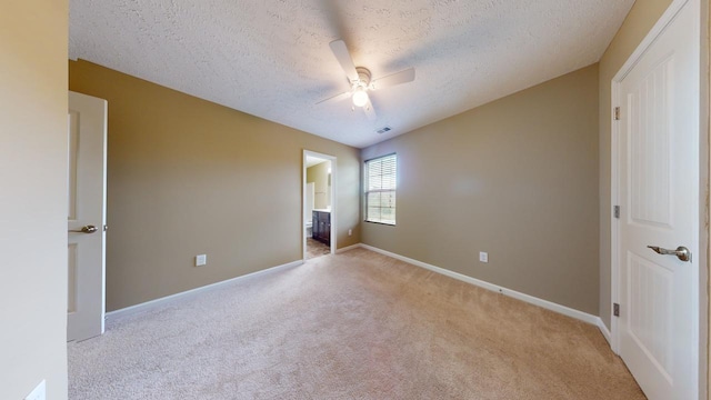 unfurnished bedroom featuring a textured ceiling, ceiling fan, light carpet, and connected bathroom