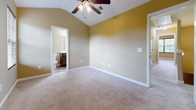 unfurnished bedroom featuring vaulted ceiling, light colored carpet, ensuite bath, and ceiling fan