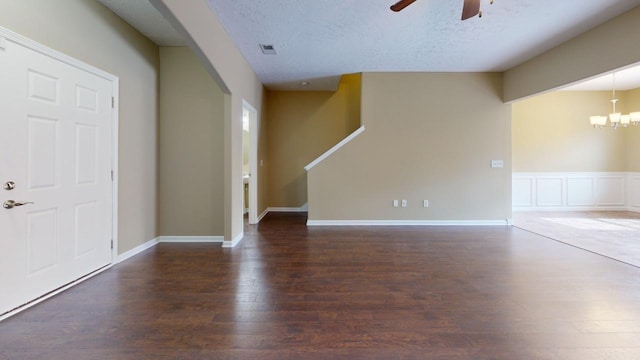 interior space with a textured ceiling, ceiling fan with notable chandelier, and dark wood-type flooring