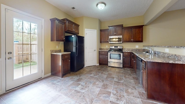 kitchen featuring light stone countertops, dark brown cabinetry, stainless steel appliances, and sink