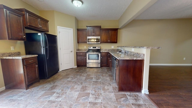 kitchen featuring sink, light hardwood / wood-style flooring, appliances with stainless steel finishes, light stone counters, and dark brown cabinetry