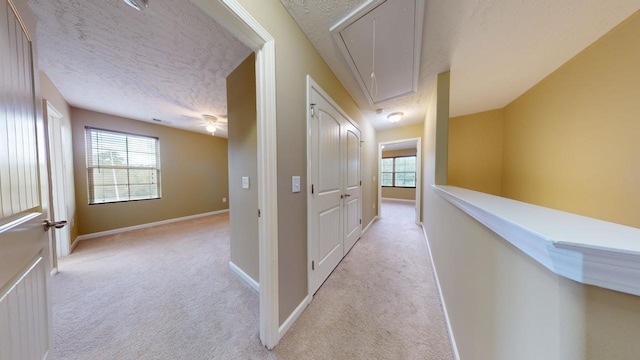 corridor with light carpet and a textured ceiling