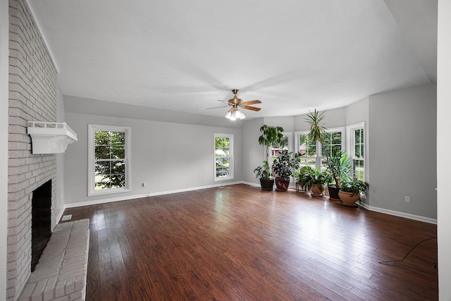 unfurnished living room with a brick fireplace, ceiling fan, and dark wood-type flooring