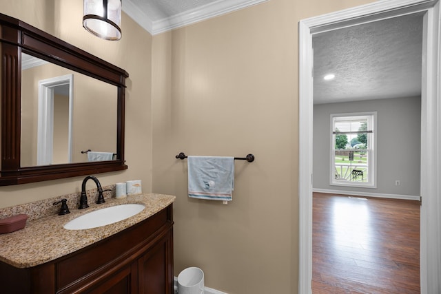 bathroom with vanity, crown molding, wood-type flooring, and a textured ceiling