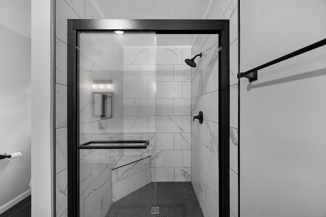 bathroom with a shower with shower door and a textured ceiling