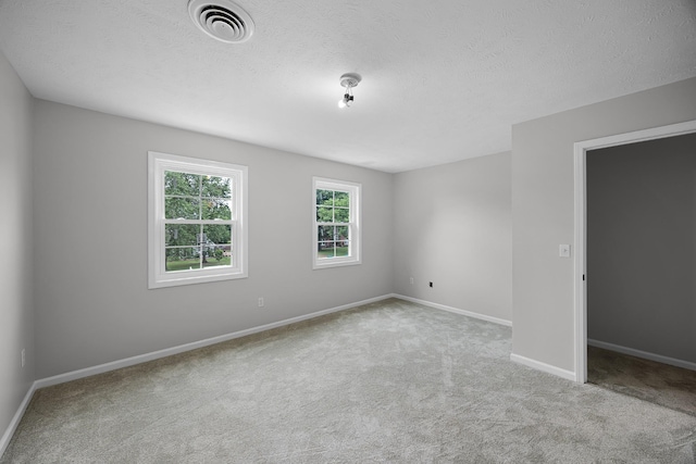 empty room with light colored carpet and a textured ceiling