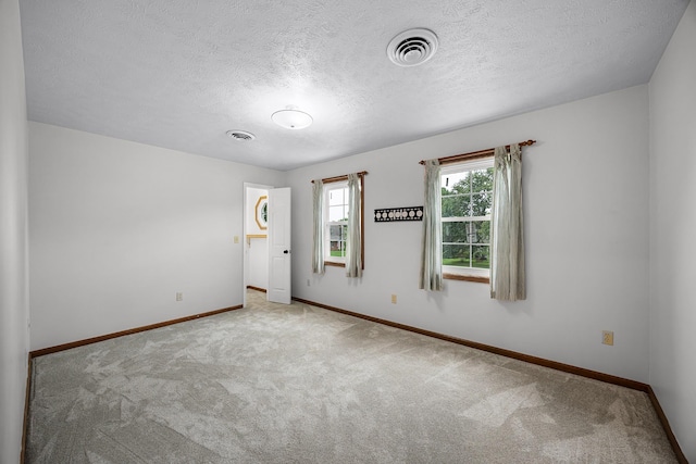 carpeted empty room with a textured ceiling