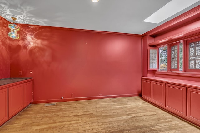 unfurnished dining area featuring a skylight and light wood-type flooring