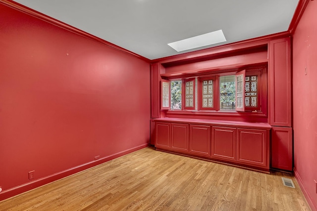 empty room featuring light wood-type flooring and crown molding