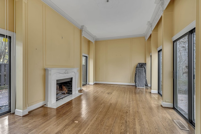 unfurnished living room featuring light wood-type flooring, crown molding, and a healthy amount of sunlight