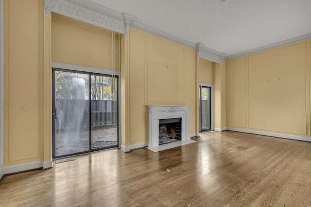 unfurnished living room featuring hardwood / wood-style floors, a premium fireplace, and crown molding