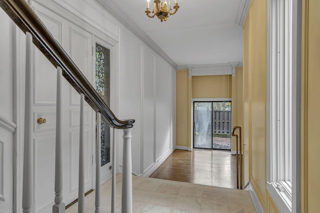 entryway with a chandelier, light hardwood / wood-style flooring, and crown molding