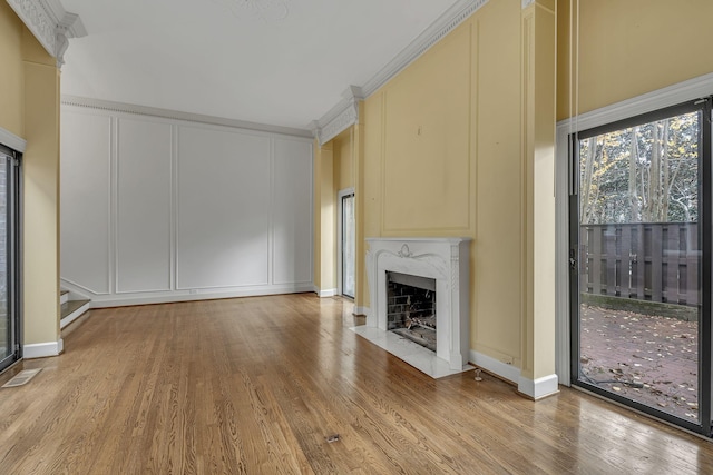 unfurnished living room with a premium fireplace, ornamental molding, and light hardwood / wood-style flooring