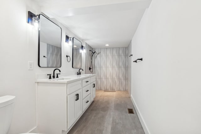 bathroom with vanity, toilet, wood-type flooring, and a tile shower