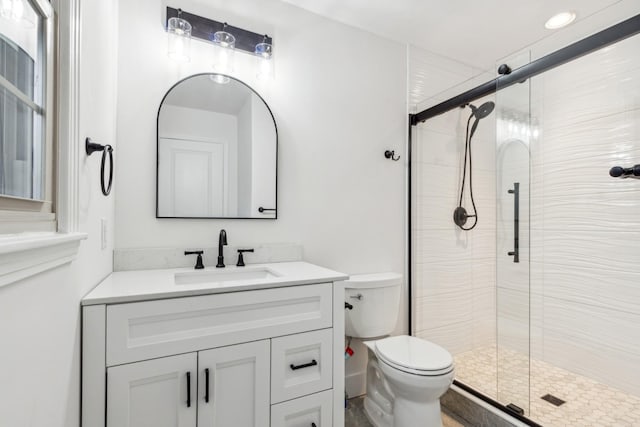 bathroom featuring vanity, a shower with shower door, and toilet