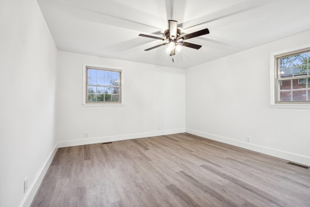 unfurnished room featuring a wealth of natural light, ceiling fan, and light wood-type flooring