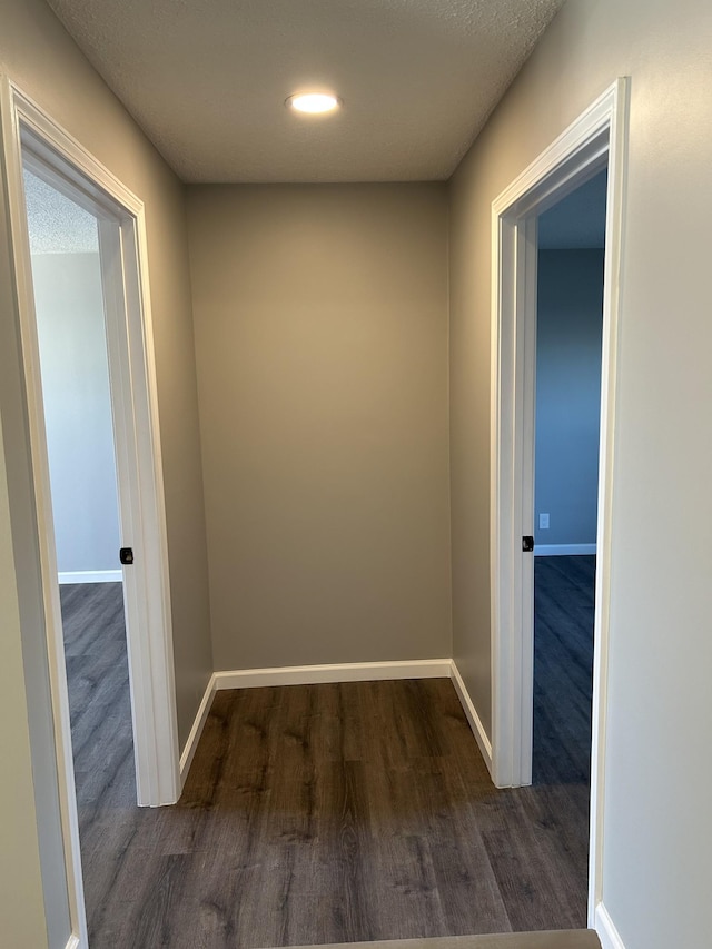 corridor with dark wood-type flooring and a textured ceiling