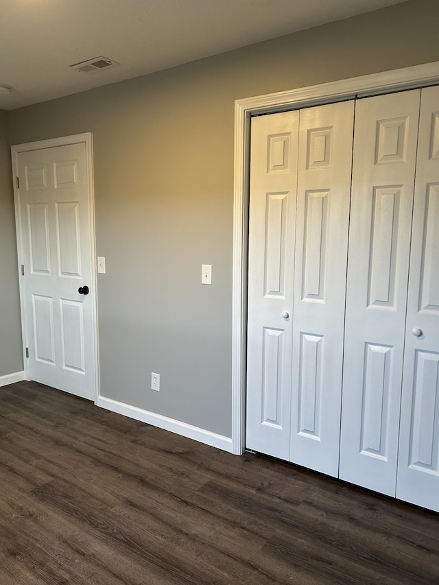 unfurnished bedroom featuring a closet and dark wood-type flooring