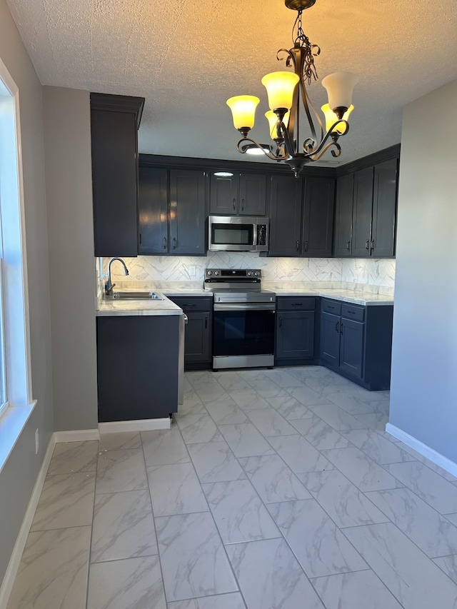 121 Poplar St N, Cowan, TN 37318 - kitchen featuring appliances with stainless steel finishes, a chandelier, light marble finish flooring, light countertops, and backsplash