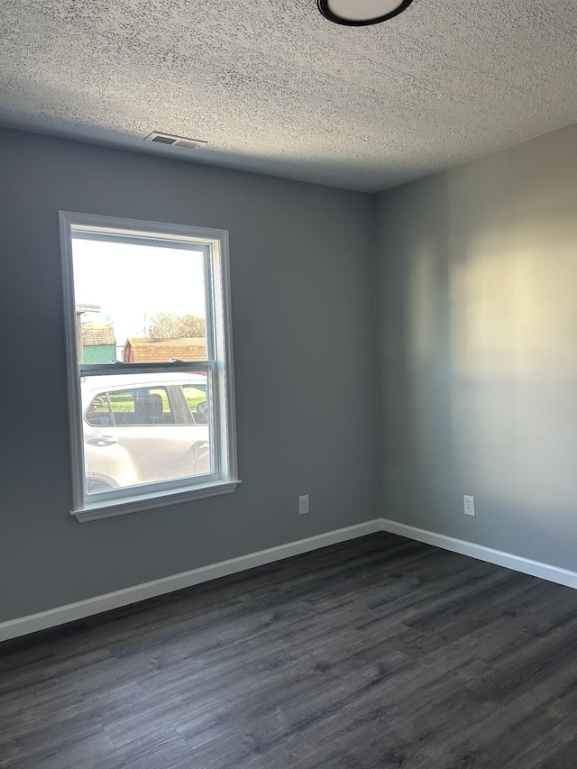 empty room featuring a textured ceiling and dark hardwood / wood-style floors