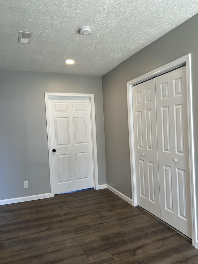 unfurnished bedroom with a closet, dark wood-type flooring, and a textured ceiling