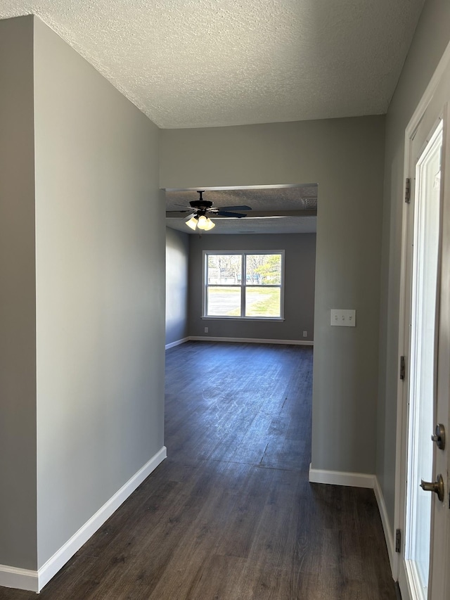 empty room with a textured ceiling, dark hardwood / wood-style flooring, and ceiling fan