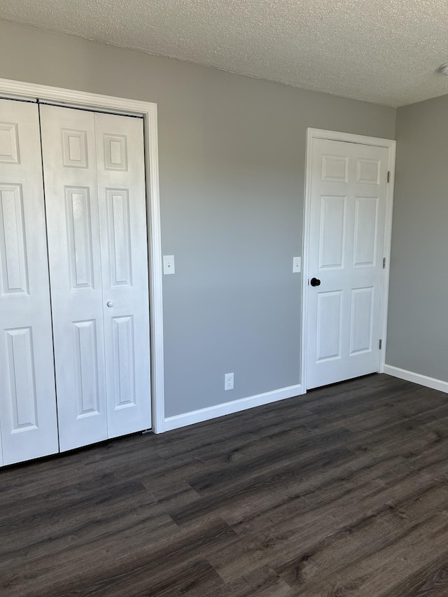 unfurnished bedroom featuring dark hardwood / wood-style floors, a textured ceiling, and a closet