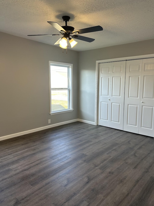 unfurnished bedroom featuring a textured ceiling, ceiling fan, dark wood-type flooring, and a closet