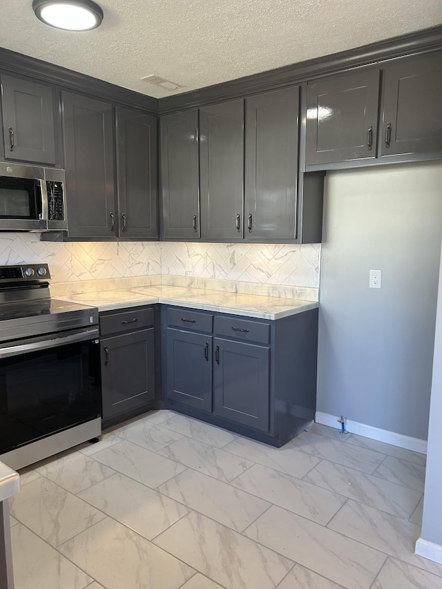 kitchen featuring a textured ceiling, stainless steel appliances, and tasteful backsplash