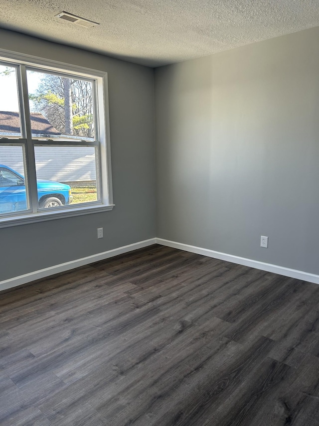 empty room featuring a textured ceiling and dark wood-type flooring