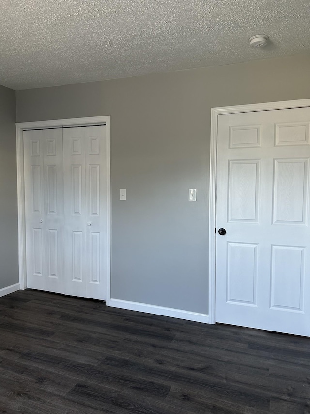 unfurnished bedroom with a textured ceiling, a closet, and dark hardwood / wood-style floors