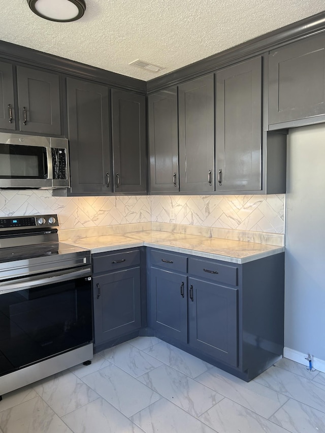 121 Poplar St N, Cowan, TN 37318 - kitchen with stainless steel appliances, light marble finish floors, light countertops, a textured ceiling, and backsplash