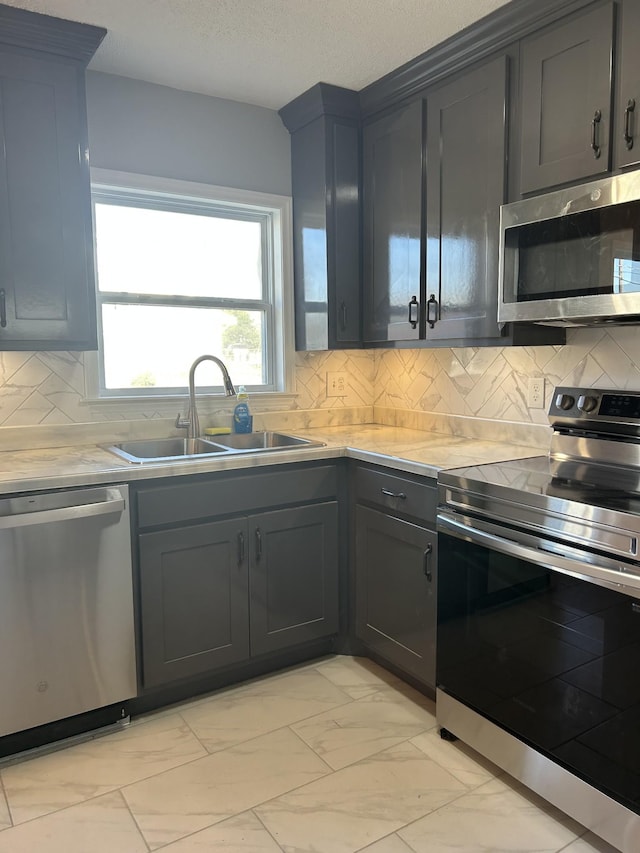 kitchen featuring a textured ceiling, sink, appliances with stainless steel finishes, and tasteful backsplash