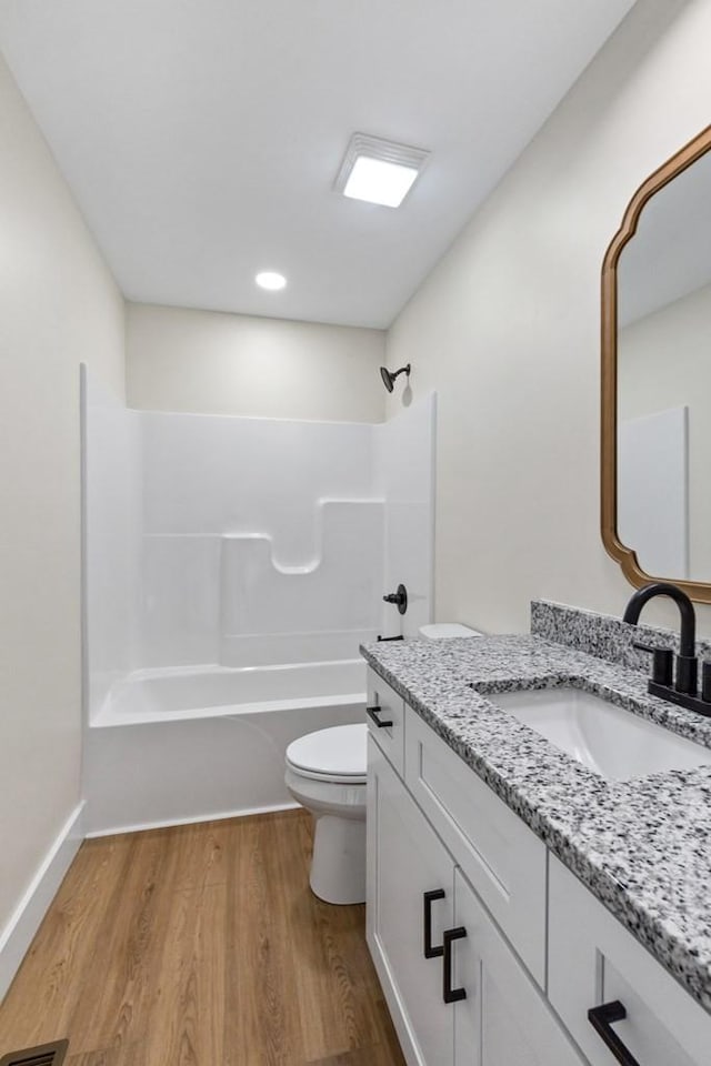 full bathroom featuring vanity, hardwood / wood-style flooring, toilet, and washtub / shower combination