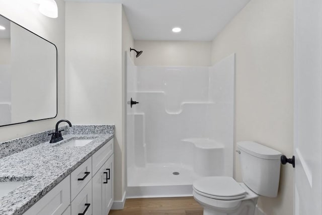 bathroom with toilet, wood-type flooring, vanity, and walk in shower