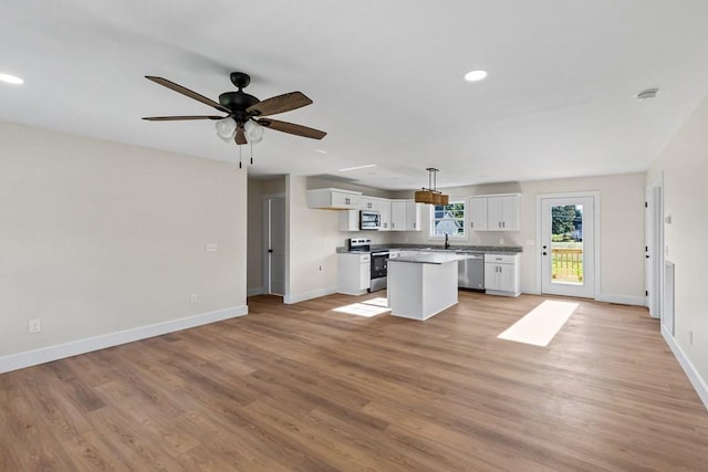 kitchen featuring white cabinetry, decorative light fixtures, appliances with stainless steel finishes, a kitchen island, and light hardwood / wood-style floors