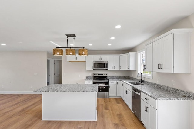 kitchen featuring a kitchen island, appliances with stainless steel finishes, pendant lighting, white cabinetry, and sink